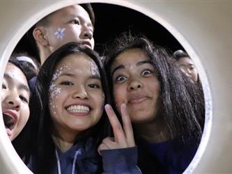 Students cheer on their team through a noise maker